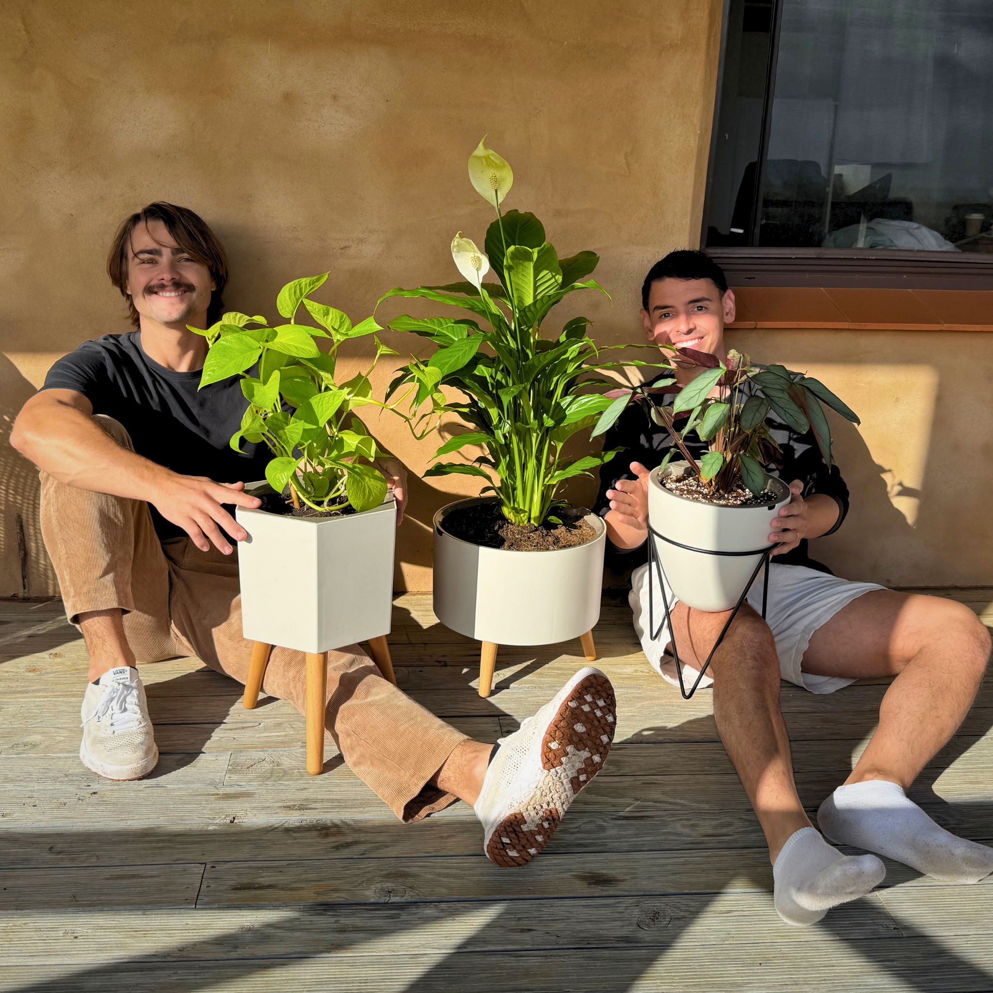 Shot of Thirstypot Family, egg, classic and hexagon, with thirstypot founders holding pots on balcony